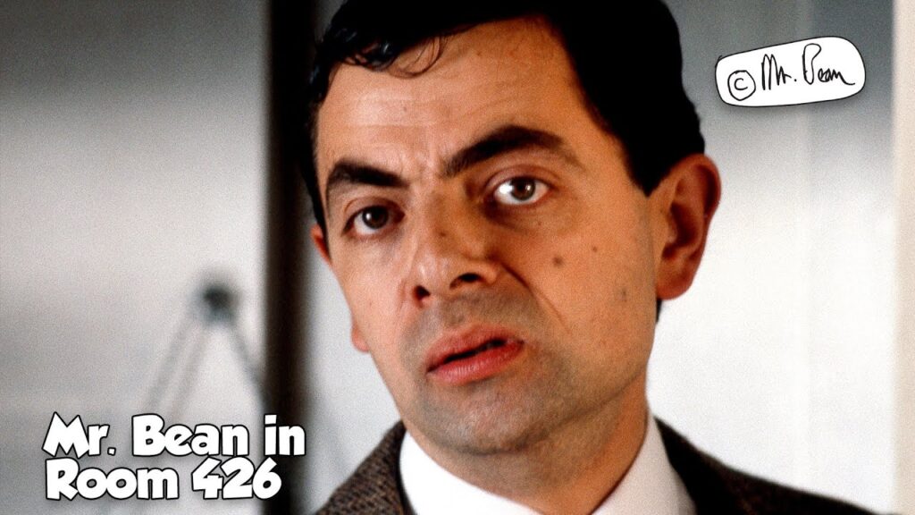 mr bean in a brown coat in a hotel room lobby
