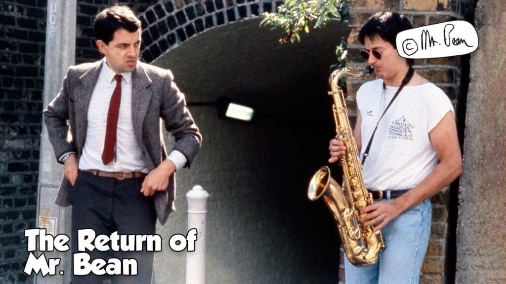 mr bean standing next to a guy playing the trumpet