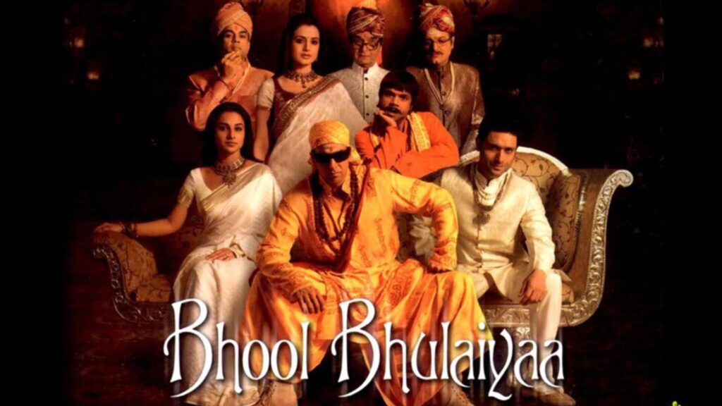 actor akshay kumar with sunglasses and yellow clothes sitting on a couch with his family and friends around including vidhya balan in bhool bhulaiyaa movie